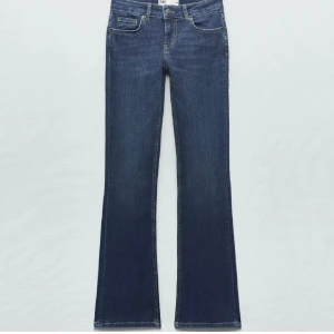 Mörkblå bootcut jeans från Zara - Säljer ett par mörkblå bootcut jeans från Zara med låg midja. Jeansen har klassisk femficksdesign, dragkedja och knapp framtill. Snygg passform som sitter tajt upptill och släpper ut vid benslutet. Perfekta för dig som gillar en retro vibe.