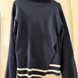 Mörkblå randig stickad tröja Weekday - Säljer en mörkblå stickad tröja från Weekday i storlek S. Tröjan har vita ränder längst ner och på ärmarna, samt en högre halsringning. Perfekt för dig som gillar en clean och stilren look.