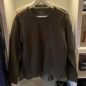 Olivgrön sweatshirt från Polo Ralph Lauren - Säljer en olivgrön sweatshirt från Polo Ralph Lauren med klassisk rund hals och diskret broderad logga på bröstet. Skulle säga att den mer är som xs
