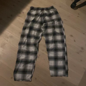 Rutiga mjukisbyxor i bomull - Säljer ett par sköna mjukisbyxor med svart, grått och vitt rutmönster. Byxorna har resår i midjan och är tillverkade i mjuk bomull, perfekta för chill dagar hemma.