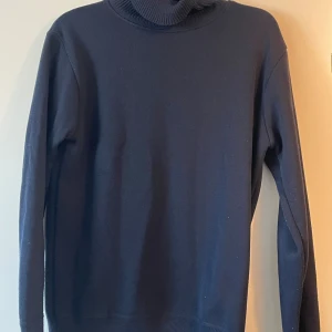 Polotröjor i mörka toner, 3-pack - Tre stilrena polotröjor i mörkblått, grått och svart. Alla har hög, ribbad polokrage och lång ärm. 