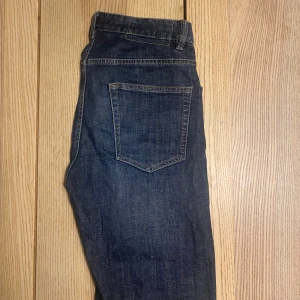 Blå jeans från Hampton Republic W30 L32 - Snygga blå jeans från Hampton Republic med klassisk femficksdesign och kontrastsömmar. Jeansen har normal passform och är tillverkade i slitstarkt bomullstyg. Perfekta för en avslappnad och stilren look.