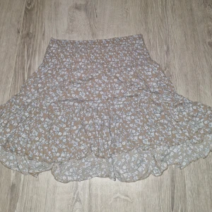 Snygg kjol från lager 157 - Ett söt beige och blå blommig kjol från lager 157 i storlek M. Använd ca 2 gånger. Köpt för 150 kr. Säljer för 30 kr.