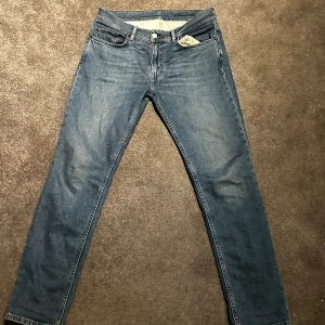 Blå jeans från Acne Studios 33/30 - Snygga blå jeans från Acne Studios i klassisk rak modell. Jeansen har fem fickor, normal passform och är tillverkade i 98% bomull och 2% elastan för lite stretch. Perfekta för dig som gillar stilrena och tidlösa jeans.
