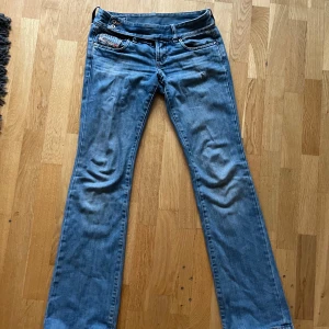 Blå lågmidjade jeans från Diesel Industry - Säljer ett par klassiska blå jeans från Diesel Industry med snygga detaljer. Modellen har låg midja, utsvänga ben och coola fickor. Jeansen är tillverkade i slitstarkt denim och har metallknappar med Diesel-logga. Jag säljer dessa för att de är tyvärr för små på mig😢😢Du kan ställa frågor om du undrar över något 😍😍💋