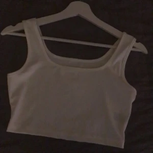 Vit croppad linnetopp - Säljer en enkel och fräsch vit croppad linnetopp med breda axelband. Toppen har en rak och stilren form som är lätt att matcha med olika outfits. Perfekt för varma dagar och chill stunder. Materialet känns mjukt och bekvämt mot huden.