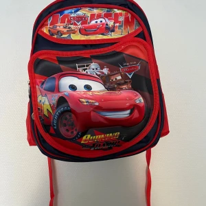 Cars ryggsäck med Lightning McQueen - Säljer en cool ryggsäck med motiv från Cars och Lightning McQueen. Väskan är röd och mörkblå med flera fack, dragkedjor och sidoficka i mesh. Perfekt för skolan eller utflykten, med färgglad design och bekväma axelband.