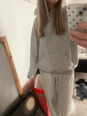 Grå hoodie med ficka - En basic grå hoodie med huva och dragsko, samt en stor magficka framtill. Hoodien har ribbade muddar vid ärmslut och nederkant. Perfekt för chill dagar eller när du vill ha en enkel och clean look. Materialet känns mjukt och bekvämt.