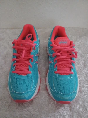 Turkosa och orange sneakers från Asics - Säljer ett par snygga sneakers från Asics i turkos med orange detaljer och snörning. Skorna har meshmaterial för bra ventilation och en vit sula med rosa inslag. Perfekta för dig som gillar färgglada och sportiga skor. Använda endast 1 gång då de inte passar mina fötter alls.