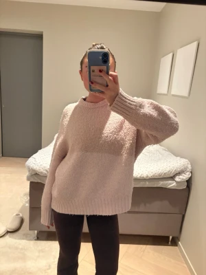 Ljusrosa oversized stickad tröja - Mysig ljusrosa stickad tröja med oversized passform och rund hals. Tröjan har långa ärmar och breda ribbade muddar vid ärmslut och nederkant. Perfekt för lager-på-lager och chill dagar.