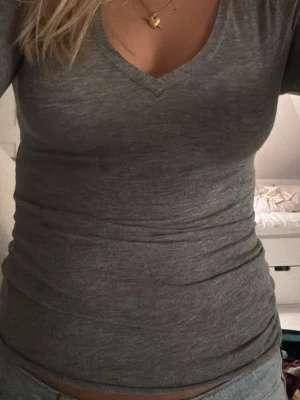 Grå v-ringad långärmad intimissimi kashmir topp - En enkel och stilren grå långärmad intimissimi kashmir topp med v-ringning. Sitter skönt mot kroppen. Perfekt att matcha med jeans eller kjol för en clean look.