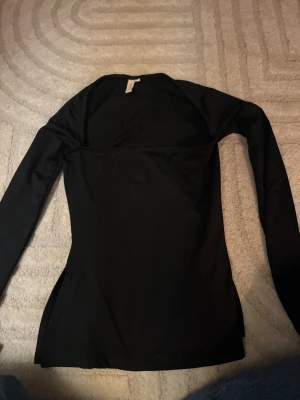 Svart långärmad topp från Nelly - En stilren svart långärmad topp från Nelly. Storlek Xs, använd 1 gång. Snygg till fest tillfällen och lätt att styla. 