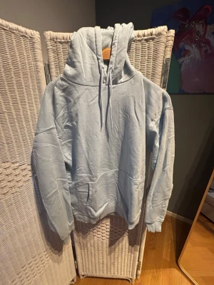 Ljusblå oversized hoodie från ASOS - Säljer en ljusblå oversized hoodie med stor huva och dragsnören. Hoodien har en klassisk känguruficka framtill och ribbade muddar vid ärmslut och nederkant. Perfekt för en chill och avslappnad stil. Materialet känns mjukt och bekvämt, troligen bomullsblandning.
