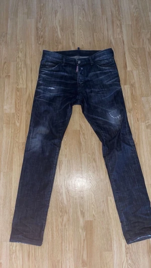 Dsquared2 Jeans Svarta - Säljer ett par svarta jeans från ds2 med snygga slitningar och raka ben. Jeansen har klassisk femficksdesign och knappgylf. Storlek 48, sparsamt använda, bra-mycket bra skick. Kan gå ner i pris vid snabb affär. Kvitto finns.
