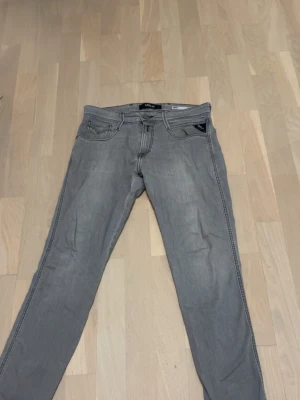 Grå Replay Anbass jeans herr - Snygga grå jeans från Replay, modell Anbass. Klassisk femficksdesign med normal passform och raka ben. Jeansen har diskreta sömmar och en liten Replay-logga på fickan. Tillverkade i mjuk bomullsdenim med lite stretch för extra komfort.
