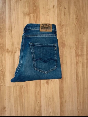 Blå Replay jeans med raka ben - Snygga blå jeans från Replay med klassisk femficksdesign och raka ben. Jeansen har en tydlig Replay-lapp bak i midjan och diskreta slitningar framtill för en cool look. Tillverkade i slitstarkt denimtyg som passar perfekt till vardagsstilen.