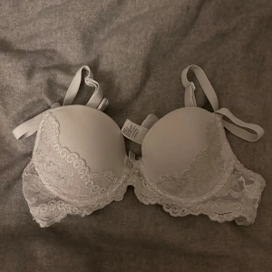 Vit spets-bh - Säljer en elegant vit bh med spetsdetaljer. Den har justerbara axelband och en mjuk kupa för extra komfort. Perfekt för att känna sig både bekväm och stilren. I storlek 65 A🩷