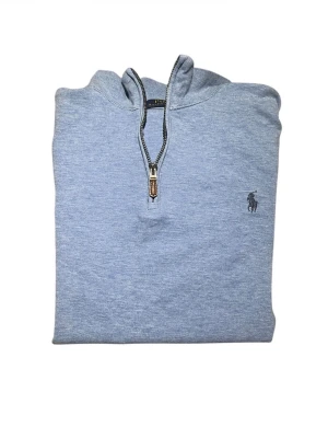 Ljusblå half zip tröja Polo Ralph Lauren - Säljer en ljusblå långärmad tröja från Polo Ralph Lauren med klassisk broderad logga på bröstet. Tröjan har en snygg half zip-dragkedja och är gjord i mjuk bomull. Perfekt för dig som gillar stilrena och bekväma plagg.