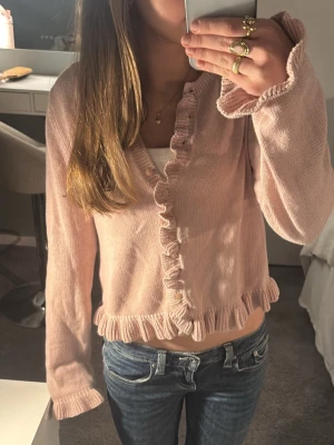 Ljusrosa kofta med volangdetaljer - Supersöt ljusrosa kofta med volang längs knäppningen och nederkanten. Från stradivarius och kommer inte till användning💗använd endast en gång💓