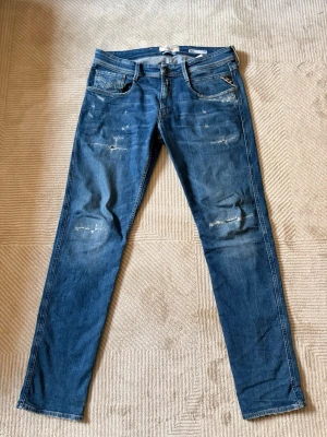 Blå Replay jeans med slitningar - Snygga blå skinny jeans från Replay med slitna detaljer på framsidan. Säljer dessa då de är för små. Ändast använda ca 3-5 gånger. Jag är 185 och de va bra i längden men satt lite för tight på mig. Skriv ifall du har någon fråga eller vill se hur de sitter på.