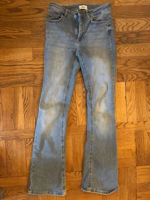 Ljusblå bootcut jeans från Only - Säljer ett par ljusblå bootcut jeans från Only med klassisk femficksdesign och normal passform. Jeansen har en snygg tvättad look och är tillverkade i mjukt bomullsmaterial med lite stretch. Perfekta för dig som gillar en avslappnad men trendig stil.
