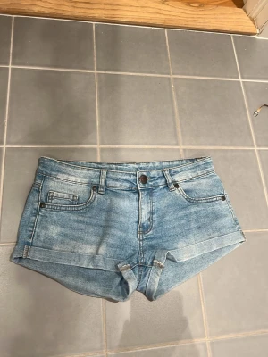 lågmidjade blå shorts  - Snygga blå lågmidajde denimshorts och uppvikta benslut. Shortsen har knapp och dragkedja framtill samt bälteshällor. Perfekta för varma dagar och enkel att matcha med olika toppar. Aldrig använda köpte i spanien 💕🇪🇸
