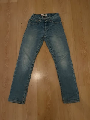 Levi's 512 Slim Tapered ljusblå jeans - Säljer ett par Levi's 512 Slim Tapered jeans i ljusblå tvätt. Klassisk femficksmodell med smal passform och avsmalnande ben. Jeansen har snygga slitningar och kontrastsömmar. Perfekta till sneakers och hoodie för en chill look.