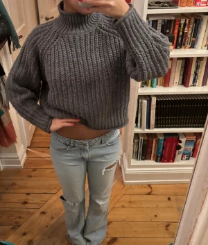 Grå stickad polotröja - Säljer en chunky grå stickad polotröja med bred ribbstickning. Tröjan har en hög krage och långa, lite pösiga ärmar. 