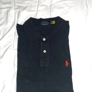 Svart pikétröja från Polo Ralph Lauren - Klassisk svart pikétröja från Polo Ralph Lauren, tröjan är  i helt nytt skick, bara testad framför spegeln! Om fler foton önskas så är det bara att fråga, 