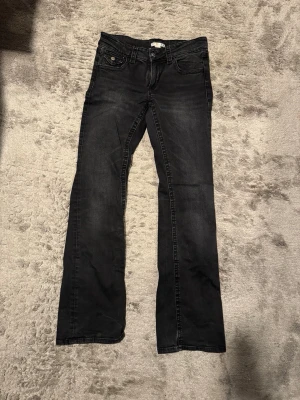 Svarta low waist bootcut jeans  - Säljer ett par svarta bootcut jeans från Gina Tricot. Använt max 5 gånger för att de var för korta på mig. (178). Jeansen har klassisk femficksdesign, knapp- och dragkedjestängning samt snygga detaljer på bakfickorna. Materialet är mjukt och stretchigt jeans-tyg för skön passform. 