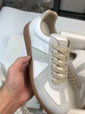 Maison margiela gats  - Säljer ett par stilrena sneakers från Maison Margiela i vitt och beige med grå mockadetaljer och beige snörning. Skorna har en klassisk siluett med rund tå och platt gummisula i brunt. Perfekta för dig som gillar minimalistisk och clean stil. Kvitto får man endast via köp!