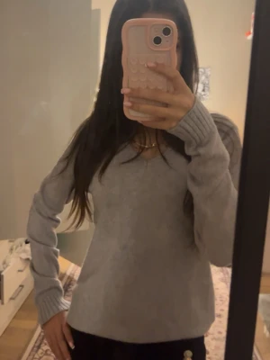 Grå v-ringad tröja från Vila - Mysig grå v-ringad tröja från Vila i storlek XS. Tröjan har långa ärmar med ribbade muddar och en klassisk passform som funkar till allt. Perfekt för lager-på-lager under kyliga dagar.