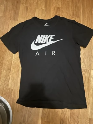 Svart Nike Air t-shirt - Säljer en svart t-shirt från Nike med stor vit Nike Air-logga på bröstet. Klassisk rund hals och korta ärmar. Perfekt för dig som gillar sportig och clean stil. Tillverkad i mjuk bomull för skön känsla hela dagen.