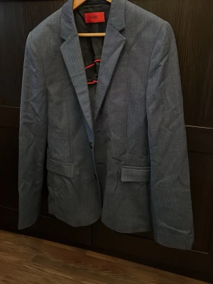 Blå kavaj från Hugo boss - Snygg blå kavaj från Hugo med diskret mönster och klassisk passform. Skriv vid frågor