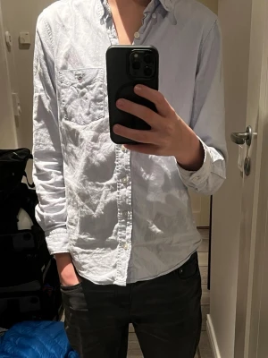 Gant Oxford  - Säljer en klassisk ljusblå oxfordskjorta från Gant.. Skjortan har knappar hela vägen, lång ärm och en stilren krage.Den har storleken 146-152 och det står 11-12 år gammal. Jag är 164 cm lång och den är för liten. Någonstans runt 160 cm och under skulle passa perfekt. Det finns en liten röd fläck vid höger arm, men syns bara på nära håll. Det finns några lösa trådar som hänger runt omkring skjortan. Skriv vid andra frågor😀