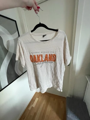Beige T-shirt med tryck  - Beige T-shirt med orange tryck från Gina Tricot 