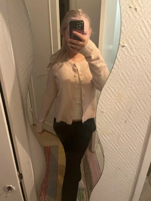 Rosa kofta från lager💗 - Säljer en söt beige kofta med rund halsringning och knappar framtill. Koftan har en mjuk och mysig känsla, perfekt att slänga på sig över en topp. Långärmad och enkel att matcha till olika outfits.