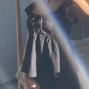 Svart blus med volangärmar och snörning - Supersöt svart blus med breda volangärmar och söt snörningsdetalj framtill från bikbok. Toppen har en lätt utsvängd passform och ett diskret blommönster. Endast använd fåtal gånger. Bara att höra av sig för fler bilder🩷