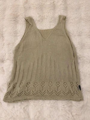 Beige stickad linnetopp från ZARA - Säljer en beige stickad linnetopp från ZARA med v-ringning och breda axelband. Toppen har ett snyggt hålmönster nertill och ribbade detaljer längs kanterna. Perfekt för en chill och trendig look.