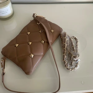 Beige quiltad axelväska med nitar liknar valentino - Snygg beige axelväska i quiltad design med guldfärgade nitar och kedjedetaljer. Väskan är oanvänd! Helt ny