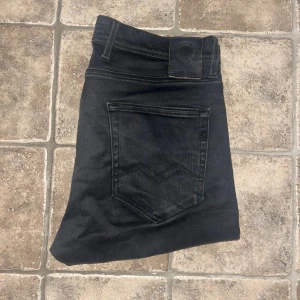 Replay jeans  - Svarta jeans från Replay i modellen EZHIR, med skinny passform. Jeansen har svarta sömmar, svarta detaljer och en snygg Replay-logga på bakfickan. Materialet är stretchigt jeans för extra komfort. Midja 42cm, längd 108cm. JAG SKICKAR EJ FLER BILDER NÄR JAG BÄR JEANSEN! för storleksguide hänvisar jag till måtten och för bättre inblick i passformen rekommenderar jag att googla på modellnamnet. Jeansen kan vara uppsydda utan att jag noterat det så kolla måtten noggrant :) s4 