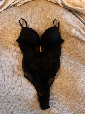 Svart spetts body - Säljer en svart spetsbody med vadderade kupor och justerbara axelband.