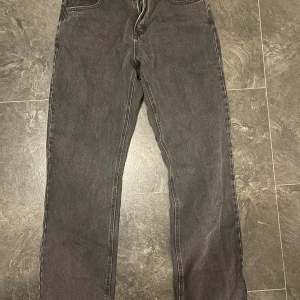 Svarta raka jeans - Säljer ett par svarta jeans med rak passform och klassiska bakfickor. Jeansen har en enkel design med dragkedja och knapp framtill. Perfekta för dig som gillar en stilren look och vill ha ett par jeans som funkar till det mesta.