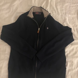 Morris zip bomull - Snygg mörkblå kofta från Morris i 100% merinoull med beige krage och hel dragkedja framtill. Klassisk design med liten broderad logga på bröstet och ribbade muddar. Perfekt för dig som gillar stilrena och bekväma plagg. står storlek M men skulle säga att den passar S bättre, hör av er vid minsta funderingar😊