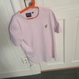Ljusrosa t-shirt från Lyle & Scott - Säljer en ljusrosa t-shirt från Lyle & Scott med klassisk passform och korta ärmar.  Den är i storlek xs. T-shirten har det ikoniska gula fågel-loggan broderad på bröstet och är gjord i mjuk bomull. Perfekt basic-plagg med stilren look.