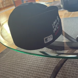 Svart White Sox keps från New Era - Snygg svart keps från New Era med White Sox-logga i vitt framtill och en liten broderad baseboll. På sidan finns texten 'Love & Hustle is Game' i vitt och rött. MLB-logga baktill. Klassisk böjd skärm och broderade ventilationshål.