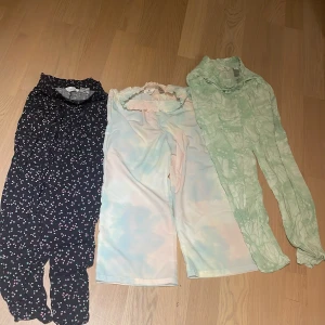 Tre mönstrade byxor från H&M, strl 164 - Säljer tre snygga byxor från H&M i storlek 164. Ett par svarta med små blommor i rosa och turkos, ett par pastellfärgade med ljusblå och rosa ton, samt ett par ljusgröna med batikmönster. Alla har resår i midjan och är gjorda i mjukt, tunt material.