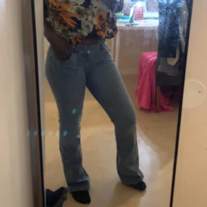 Bootcut ljusblå jeans - Snygga ljusblå jeans med bootcut passform och hög midja. Klassisk femficksmodell med bälteshällor och knappstängning. Perfekta för dig som gillar en retro vibe och vill ha ett par jeans som sitter bekvämt och framhäver benen.