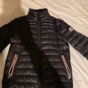 Moncler Daniel st 0 - En Moncler Daniel storlek 0. Den är många år gammal och har sina tecken på det. Den har ingen NFC tag, dessa fanns inte då, men den har en fungerande QR kod. Ett hål där bak har lappats ihop, och mindre märken finns på ärmar. Tråden som jackan hängs upp mer är av, men det är extremt lätt att fixa. Huvuddragkedjan har även bytts ut, då den gick av, men dess gamla dragkedje delar, metalldelarna med logan på, finns kvar om man vill fixa. Upphämtning eller frakt, fråga om det är något som undras.