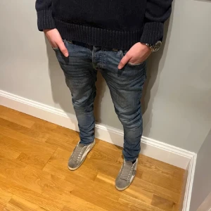 Blå jeans från Nudie - Säljer ett par klassiska blå jeans från Nudie Jeans med snygg tvätt! Modellen heter Grim Tim och det är storlek W30 L32. Grabben på bilden är 180 cm lång. Skriv gärna vid frågor eller funderingar! Notera att det har varit ett hål (se bild 4) men lagats!